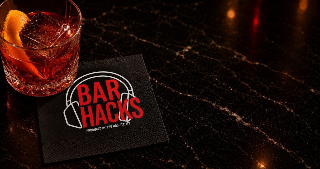 KRGNightlife_BarHacksBevNap_J Bar Hacks podcast branding on a premium cocktail napkin in an upscale bar setting.